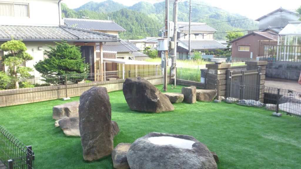 残した岩がアスレチックになり人工芝とマッチするドッグラン