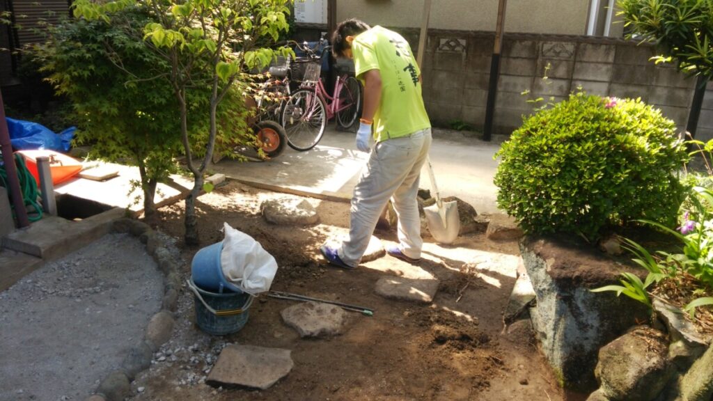 植木の枝葉が当たらない位置へ飛び石をずらして配置する様子