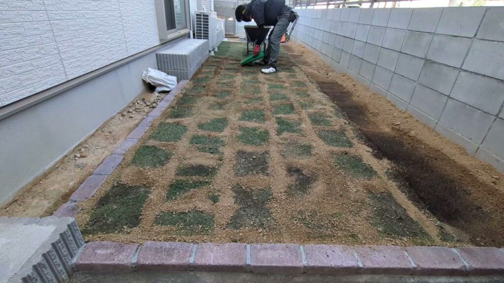 張った芝の上に目土を撒き、継ぎ目に落とし込んでいるところ