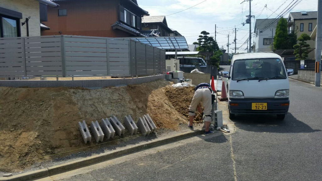 道路際で土留めブロックの基礎を掘り始めたところ。奥にカーポート