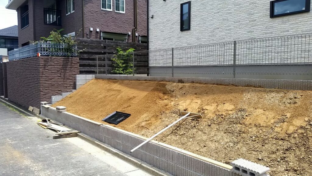 法面に入れた新しい真砂土を、トンボと板を使って上から下へならしているところ