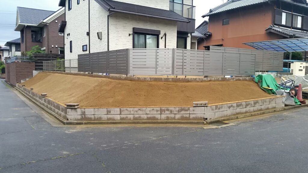 真砂土で形を整え直した法面。道路との境に2段の土留めブロック、上に目隠しフェンスが入っている