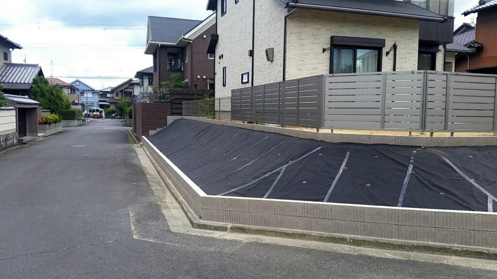 完成した法面を道路から見たところ。防草シート・2段の土留め・目隠しフェンスが入っている