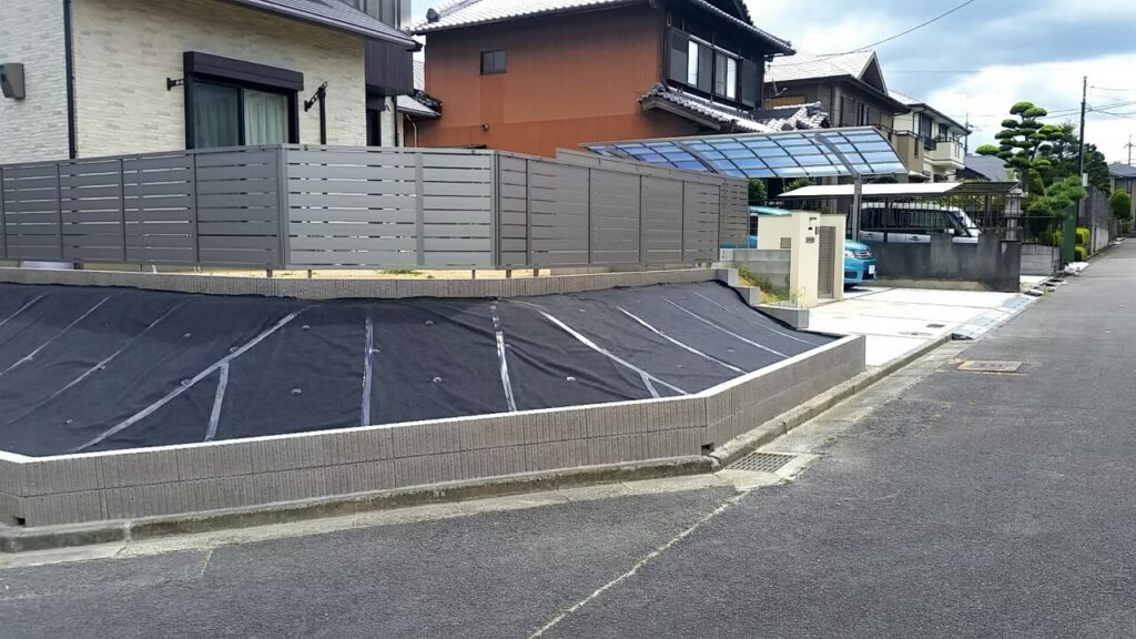 南東から見た完成後の外まわり全体。法面と目隠しフェンス、奥にカーポート